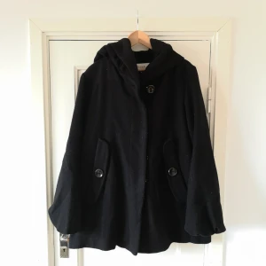  - Kappa i A-linje med stor knappar och stor luva! Luvan går att vika ner till en fluffig krage. Alla knappar behöver förstärkas men jackan i sig är i bra skick. 