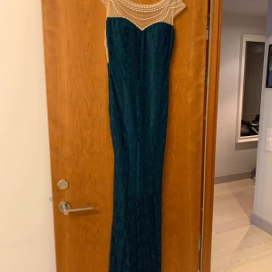 Cocktail klänning - Figursydd coctailklänning med pärlor upptill med tyll i ryggen . Färg mörkgrön