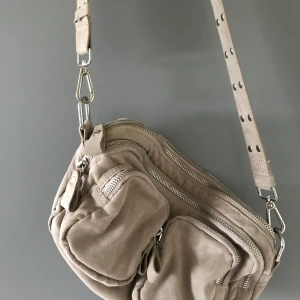 Väska - Liknande nunoo bag från Gina tricot. Inköpt förra året. Slitningar på det stora bandet men det smala är inte användt. Jättefin och rymlig. Ngn liten fläck som går att tvätta bort.