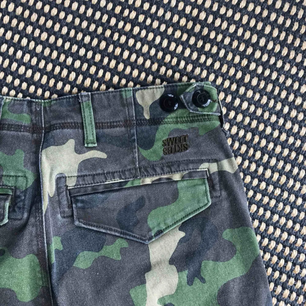 Unisex-shorts i militärmönster från SWEET SKTBS. Fickor på båda sidor. Supersköna. Använda ett fåtal ggr.. Shorts.