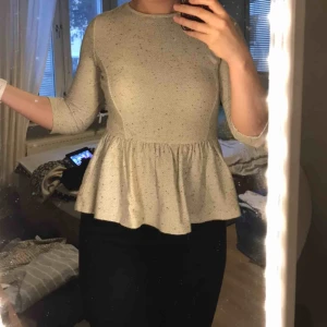  - Peplum blus i lite kraftigare material som är grå/vit/svart. Dragkedja baktill. Markerar midjan på ett fint sätt!
