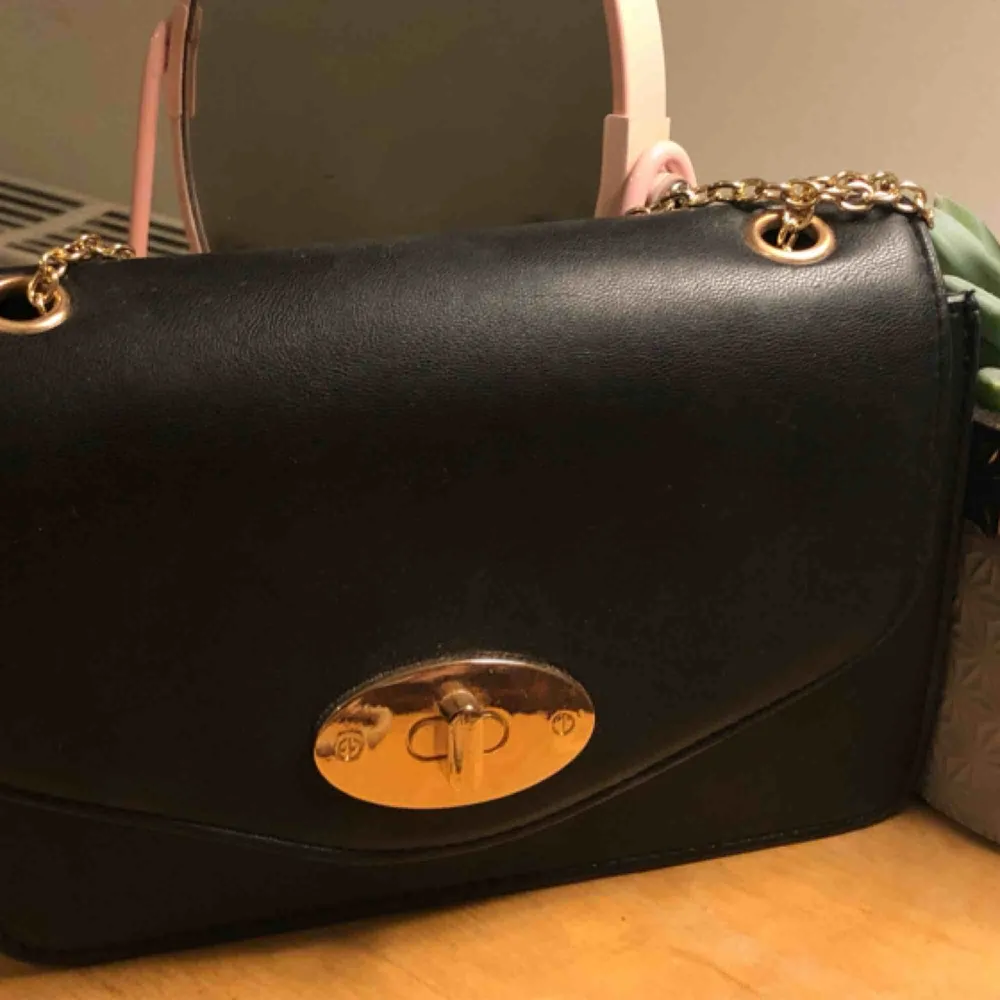 Finfin stilren väska med gulddetaljer! Kedjan går att stoppa in för att skapa en handväska istället för axelväska. Köpt på glitter och använd endast en gång. Möts upp i Sthlm, annars står köparen för frakten. 💛. Väskor.