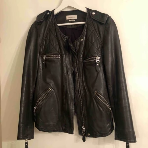  - Färg: Svart Storlek: 40 Nypris 1400kr, säljs för 700kr!  Skinnjacka i lammskinn från Isabel Marant Étoile med rundad hals, bomullsfoder, fickor med dragkedja fram, fickor med dragkedja i sidorna, quiltad effekt och ärmslut med dragkedja. 