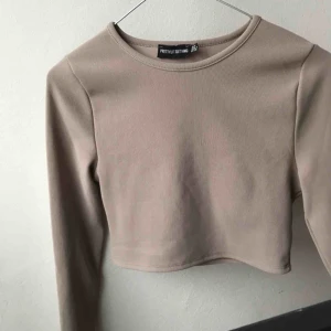  - Säljer denna beigea magtröja långärmade tröjan från Pretty Little thing. Den är oanvänd! 