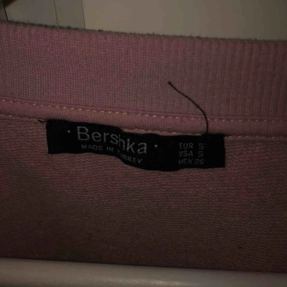 Rosa croppad sweatshirt från Bershka. Tröjan är oversized. Den har även tillgjorda hål lite överallt i tröjan vilket är en snygg detalj. Säljes pga att jag ej har användning för den. . Toppar.