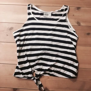  - Sjömansinspirerad top från gina tricot i storlek medium. Randig i vit och marinblå med en knut längst ner.