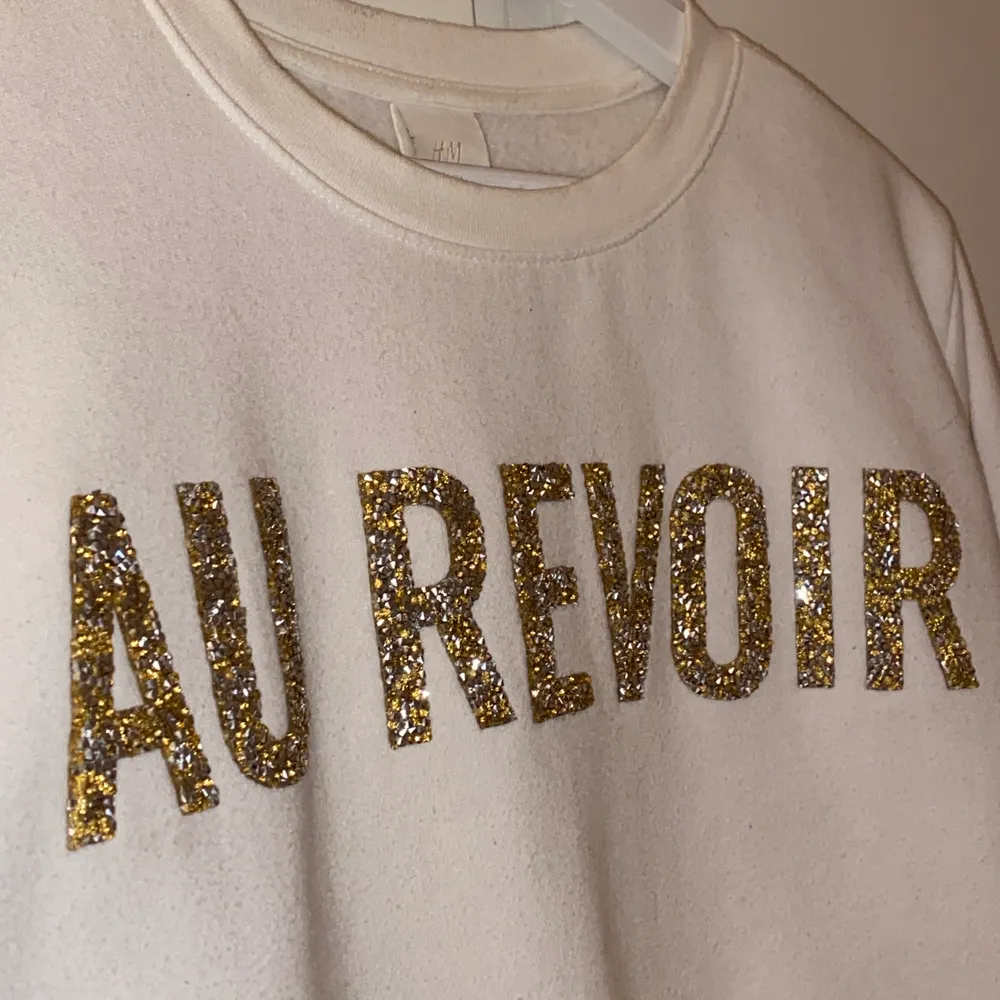 Vit collagetröja med texten ”Au revoir” (hejdå på franska) i guld och silver glitter. Använd max 4 gången, i toppen skick🤎🤗. Tröjor & Koftor.