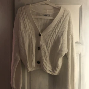 Stickad tröja/kofta - Säljer min oanvända hollister stickade kofta som endast legat i garderoben. Helt ny och vit med bruna knappar. Älskar att koftan är kort (ungefär över höftbenet) säljer då jag fått den men inte tyckt de va min stil💛 (storlek M men passar alla beroende hur stor/liten man vill ha den)