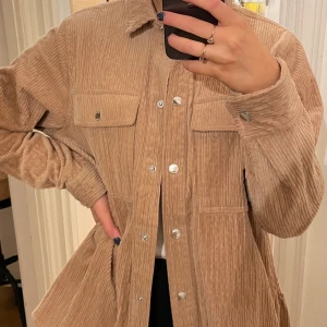 Beige manchester overshirt från Samsoe Samsoe  - Säljer en beige overshirt från märket Samsoe Samsoe, använt ett fåtal gånger. 97% bomull och 3% elastan, tyg: manchester.  Den är i storlek S men skulle passa en M också. Ordinarie pris 1399 kr.