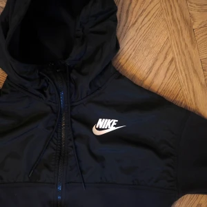Nike träningströja - Svart träningströja med luva, fickor och dragkedja. Rak och relativt tunn modell, blankt material över axlarna. Skulle säga att den passar en XS-S! Kan skickas mot frakt.