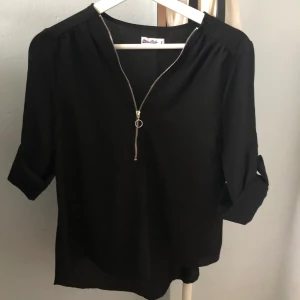 Svart blus - Fin blus i tunt somrigt material☘️ Dragkedja så att man kan anpassa urringningen, och ärmarna går att rulla upp eller ha långa