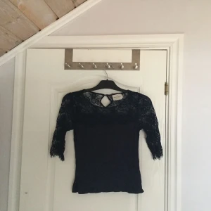  - Oanvänd mörkblå t-shirt med 3/4 arm av spets. 