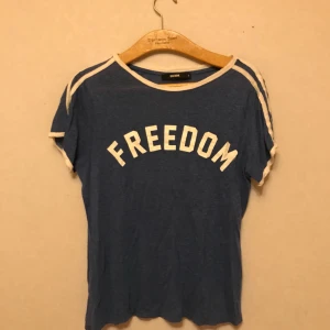  - Blå fotbollsinspirerad t-shirt från BikBok med vita tryck och två vita sträck över armarna. Väldigt mjuk och mysig. Storlek S.