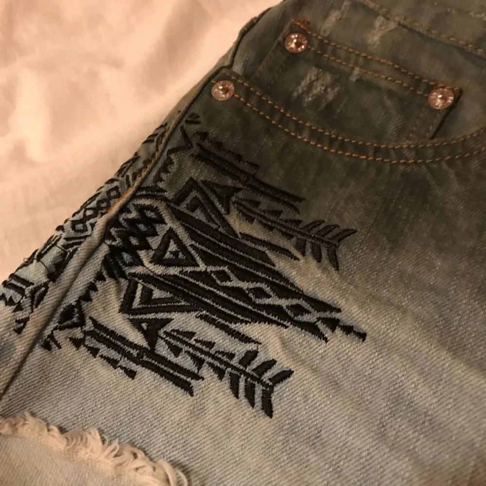 Fina jeansshorts från BikBok i storlek Medium. Ljusblå med gråa toner och snyggt broderade svarta detaljer på sidorna. Fickor fram och bak. Frakt tillkommer!. Shorts.