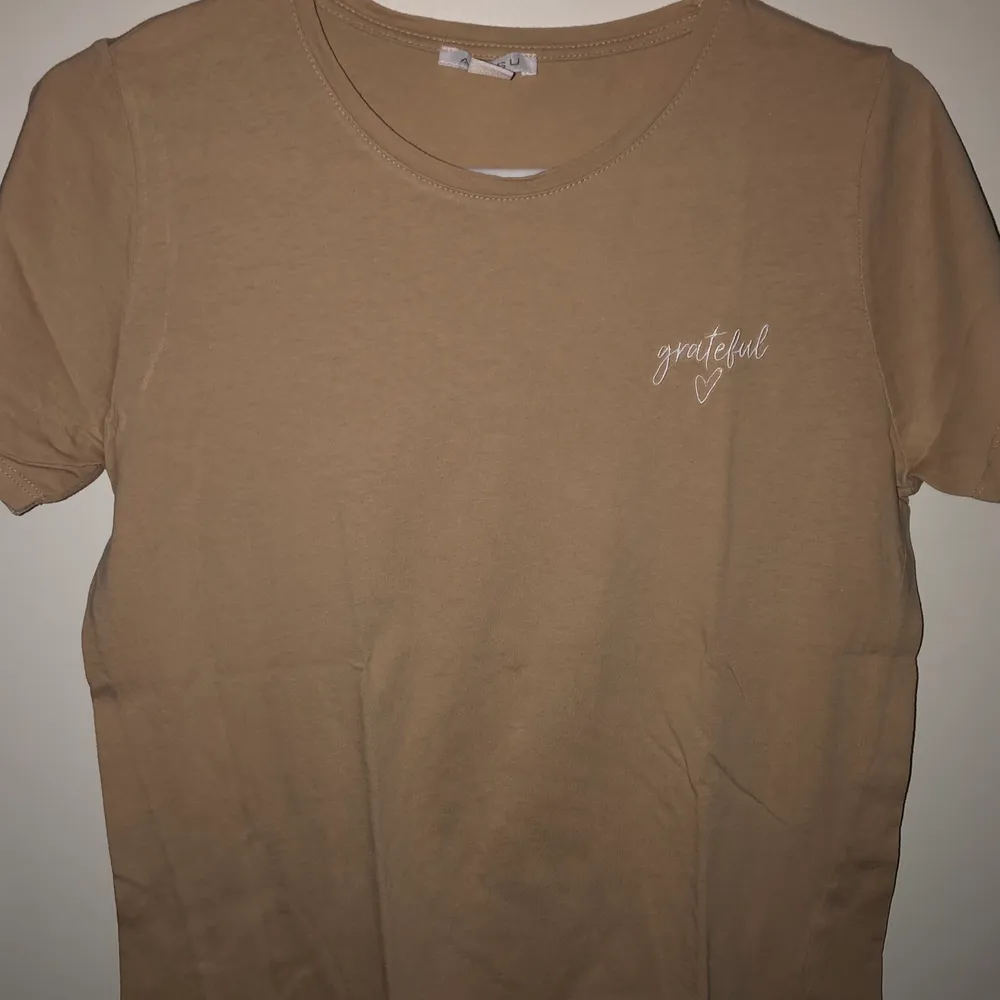 Beige t-shirt i nyskick. Aldrig använd. Texten ”grateful” på bröstet. Frakt är inkluderat i priset.. T-shirts.