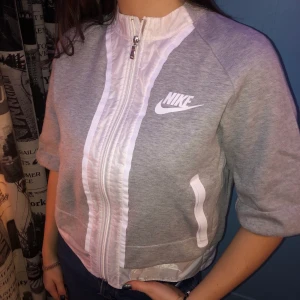 Grå Niketröja - Ljusgrå Niketröja i mycket fint skick. Knappt använd. Cool med annat, nästan lite plast/prassel, vitt material nertill än det grå som resten av tröjan. Välfungerande dragkedja. Två fickor. Kan användas till träning som till vardags. Storlek M men passar även S. 