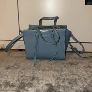 Blå zara väska - Säljer denna jättefina väska! Använt ungefär 2 gånger då jag är bekvämare med svarta väskor! Jättebra skick. Justerbart axelband!❤️ köparen står för frakten!