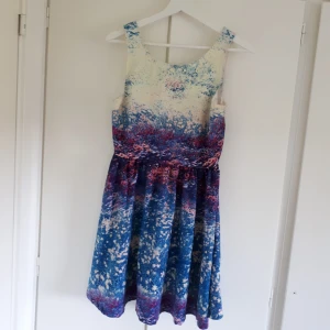  - Blommigt mönster i olika nyanser och en v-ringning baktill med dragkedja. Aldrig använd pga för stor storlek 