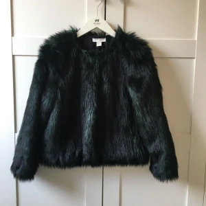  - Fuskpäls av kortare modell, dolda fickor framtill. Stängs med hyskor. Mörkgrön och svart. Kostade 899kr vid inköp, använd en gång, helt utan skavanker. 