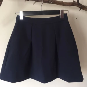  - Mörkblå vippig kjol från mango suit. Använd 1 gång så i mycket gott skick. Snygg detalj med guldig dragkedja bak.  Stl XS men passar även S.   Garderobsrensning, se mina övriga annonser.  Köparen står för frakt. Ansvarar ej för postens ev slarv.