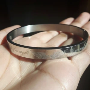  - Silverarmband från BIJOUX BY US, med ett par vingar och texten "We are each of us angels". Sätts av och på genom ett magnetfäste.