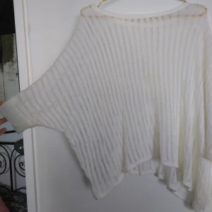 - En vit poncho med nuddar i ärmarna. Ganska transparent, men jag har haft ett linne under. Skick: Använd ett fåtal gånger. Gratis frakt!
