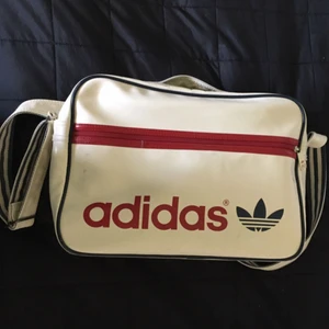  - 🌹Off-white Adidas axelremsväska med marinblå och röda detaljer. Använd och har därför några märken på ytter- och insidan men annars i bra skick samt har två fack på insidan och ett på utsidan. Köparen står för halva frakten. Priset kan diskuteras 