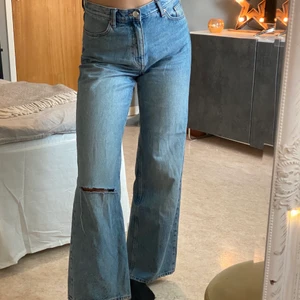 Jeans med hål - Ljusa vida jenas med hål på vänster knä från Monki, storlek 28. Buda i kommentarerna eller skriv till mig privat! Frakt tillkommer om mötas inte är möjligt!  