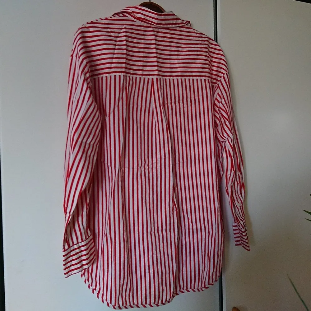 Röd- och vitrandig skjorta i nyskick. Lång modell, lite längre bak än fram. Passar 36-38. Skjortor.