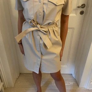 ”Skinnklänning” från bikbok - Snygg beige klänning från bikbok i skinnimmitation frpn bikbok. Oanvänd med lapp kvar. Köpt för 800kr i somras.