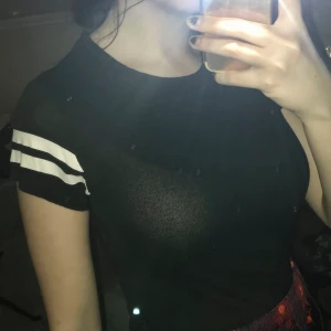 T-shirt med vit detalj - En svart T-shirt med vita streck på armarna. Använd få gånger. Säljes pga för liten för mig. Stretchigt tyg och bekvämt material. Frakt ingår!!