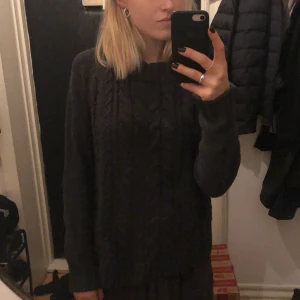 Mörkgrå stickad tröja - Mörkgrå stickad tröja med lite kabelstickat mönster framtill. Säljer för att den tyvärr inte kommer till användning.