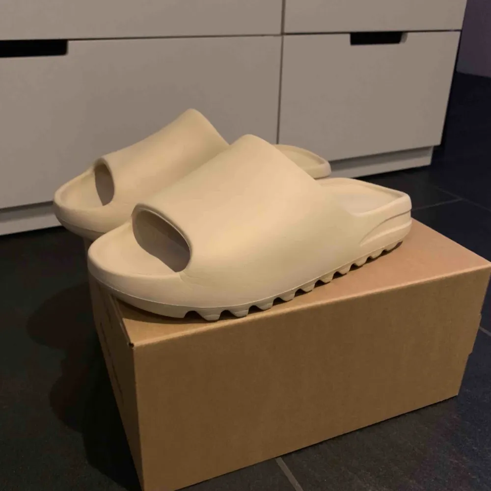 Adidas Yeezy Slides ”Bone” colourway. De är endast testade inomhus. Dom är lite små i storleken så ska passa 43-44. . Skor.