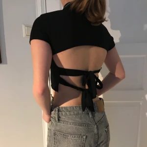 Topp med snörning i ryggen - Topp från missguided med trendig snörning i ryggen. På framsidan är den helt svart med lite högre krage. Storlek S. Köparen står för frakten som ligger på 66 kr. Hör av dig om du är intresserad eller vill ha fler bilder💞