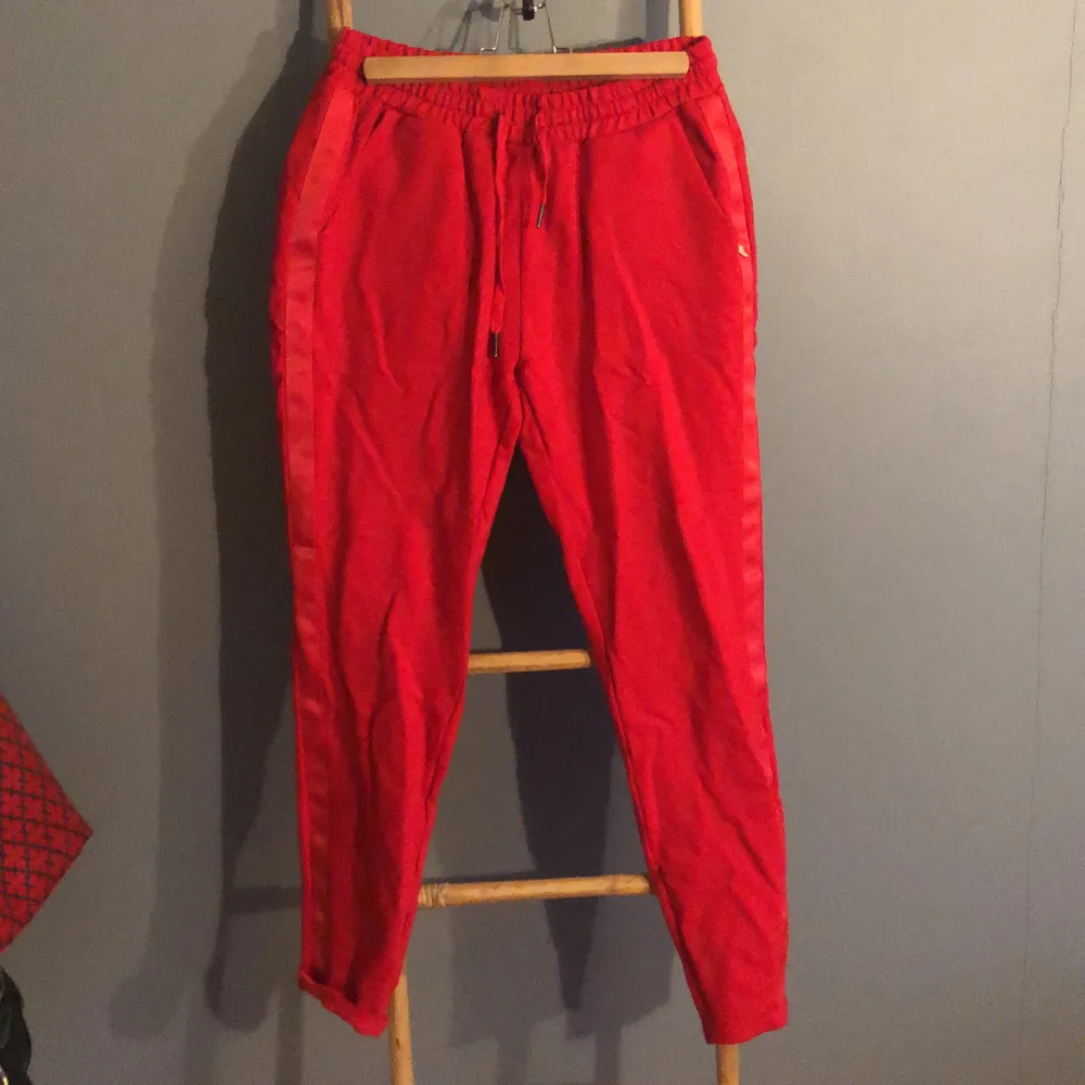 Röda Sweatpants med detaljer på sidan storlek 38.  Fickor fram och låtsats fickor bak. Använda en gång så i nysckick. Käns väldigt lyxiga. . Jeans & Byxor.