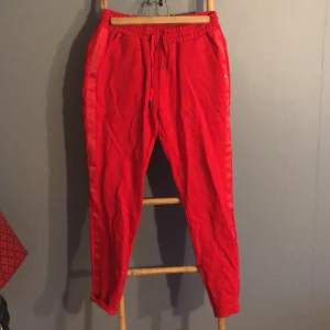 Sweatpants  - Röda Sweatpants med detaljer på sidan storlek 38.  Fickor fram och låtsats fickor bak. Använda en gång så i nysckick. Käns väldigt lyxiga. 