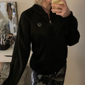 Fred Perry kofta - Svart glansig Fred Perry kofta i en sportig modell. Ganska liten i storleken då den är en 40 men snarare passar som en 36. Knappt använd och är i fint skick.