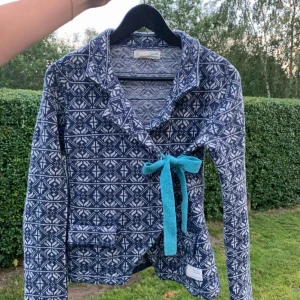  - Odd Molly stickad ull omlottkofta med knyte. Sparsamt använd, fint skick. Nypris 1200kr, säljes för 500kr inklusive frakt ( inom Sverige ). Söt mönstrad blå-vit kofta med ljusblå knytrosett. 