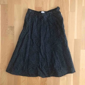  - Prickig midi-kjol som räcker till knäna. Mörkblå, nästan svart, trendig