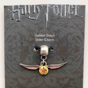  - Oanvänd berlock föreställande en golden snitch från Harry Potter-museet i London.
