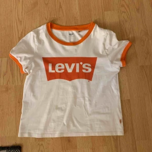  - En vit levi’s tshirt med oranga detaljer, använd fåtal gånger pga att den är för liten. Kan mötas upp i Växjö för 70 kr annars tillkommer frakt.