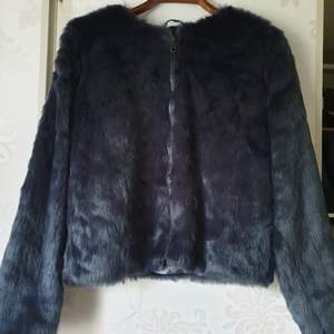 Kort faux fur jacka med dragkedja. Blå färg. 