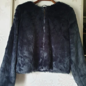  - Kort faux fur jacka med dragkedja. Blå färg. 