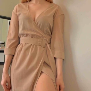  - Supersnygg beige klänning från boohoo med slits vid benet. Har ett tillhörande band som man kan knyta runt midjan 