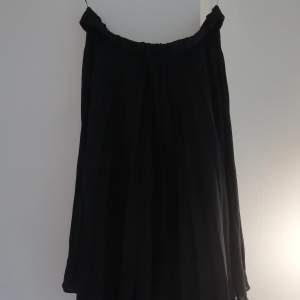 Vågig svart kjol i glansigt tyg 