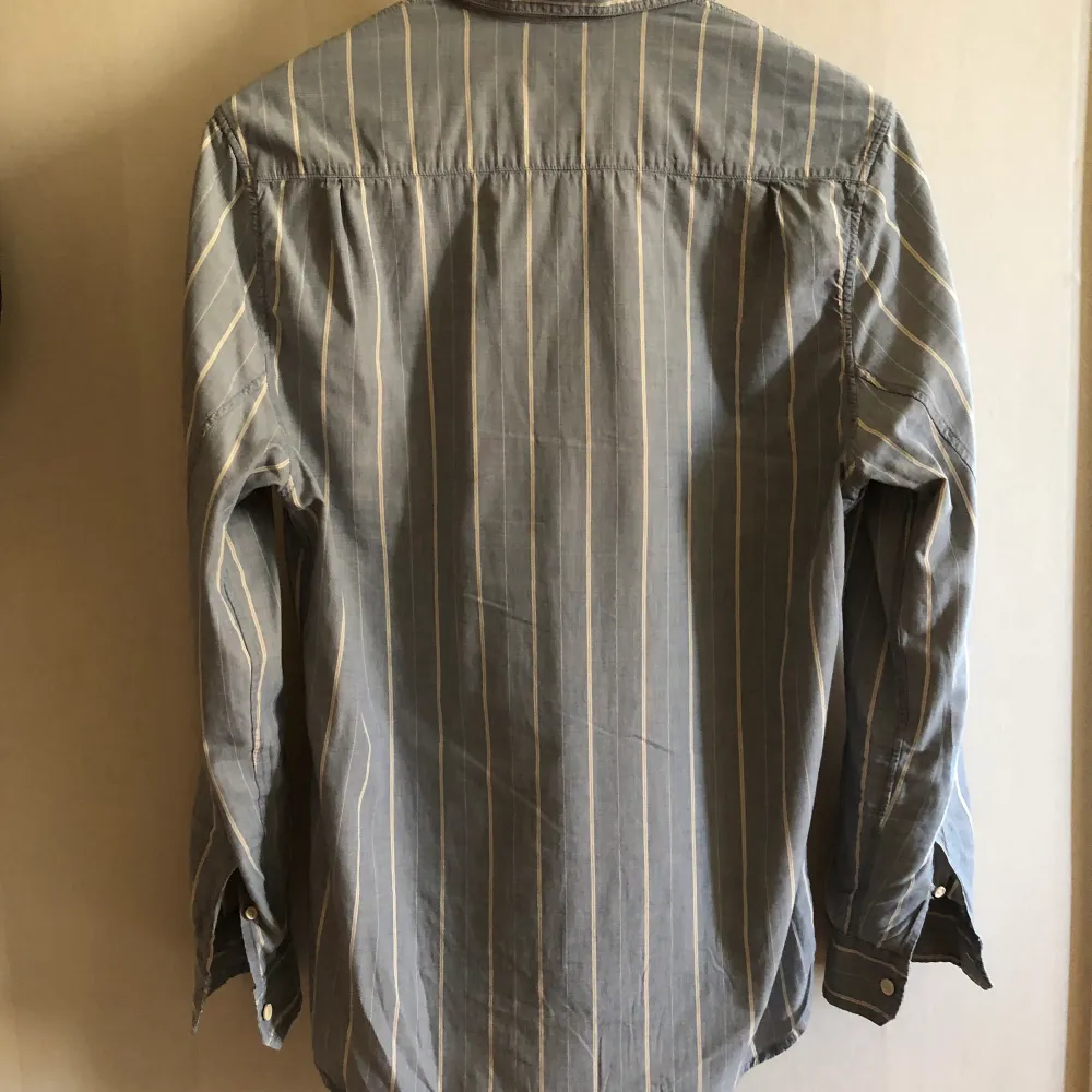 Ljusblå och vitrandig Sunset skjorta från LVC (Levis Vintage Clothing) som är en reproduktion av delar av Levis arkiv. Skjortan är knappt använd och i jättefint skick. Nypris 1699kr.. Skjortor.