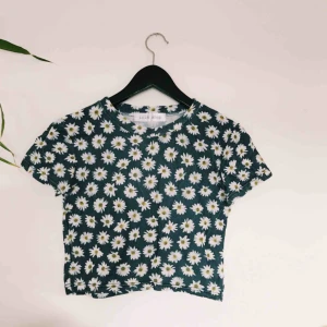  - Magtröja i blått med blommor. Ett speciellt tyg som påminner om polyester. Vet dock inte exakt vilket tyg det är. Frakt 36kr. 