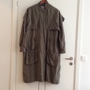  - Olivgrön parkas. Lös och lång i passformen. Knappt använd, nyskick.