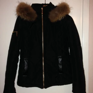  - Snygg knappt använd dunjacka från bells shoes med stor och fluffig pälskrage i äkta päls. Svart med guld detaljer. 

Kan skickas mot frakt kostnad. 