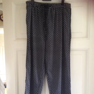  - Långa byxor i bekvämt, stretchigt tyg. Mönstret är lite bortnött i grenen. Funkar både att ha i midjan och på höfterna